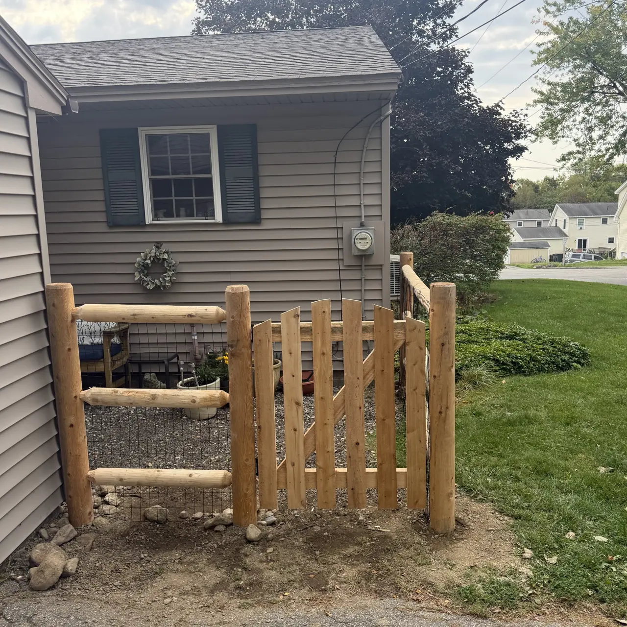 Wood pedestrian gate and rail fence beside a home