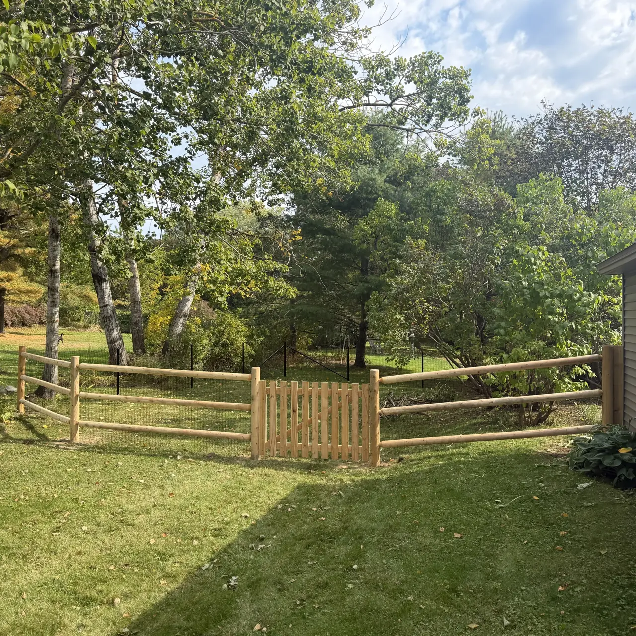 Wood rail fence and gate enclosing a lawn