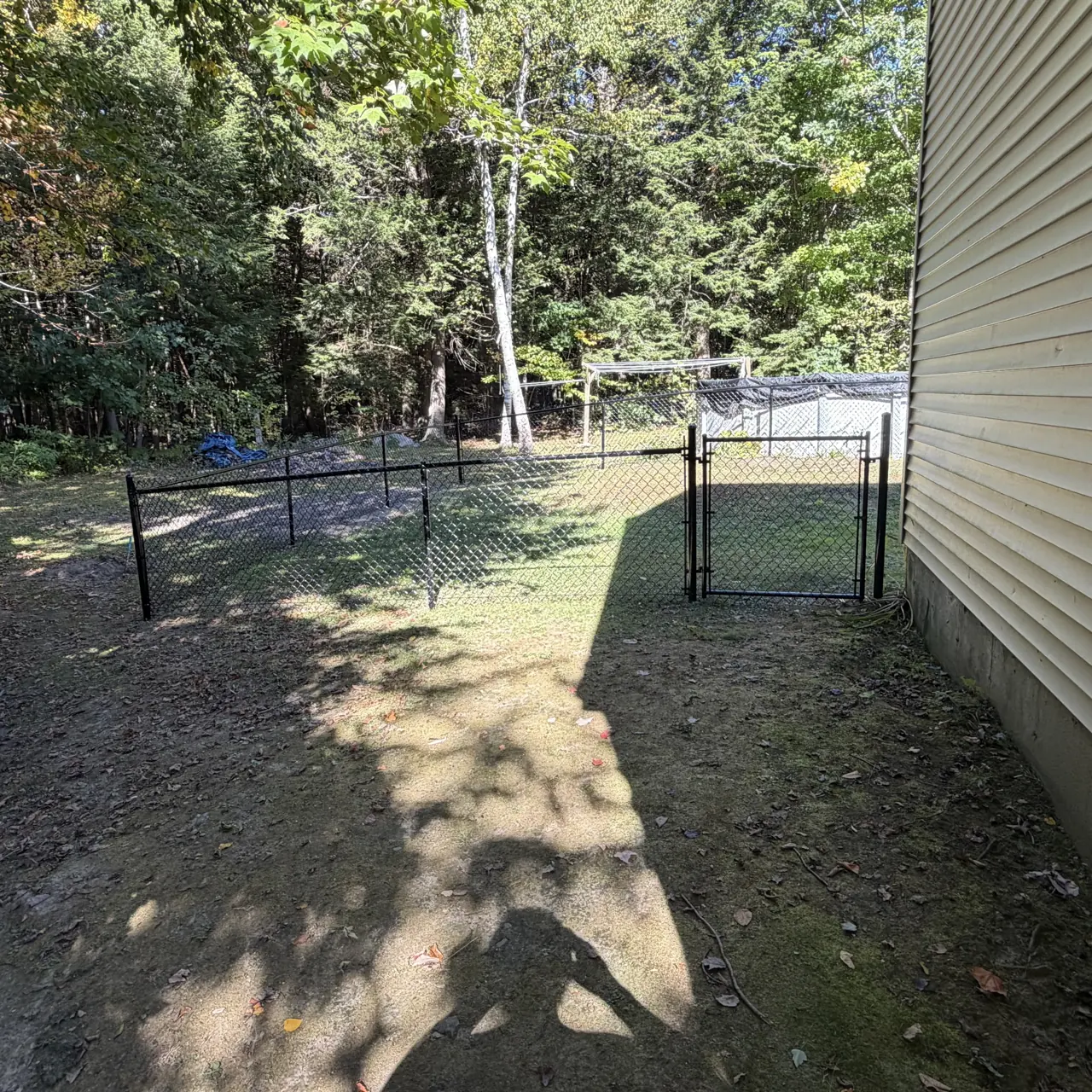 Black chain link fence and gate beside a house